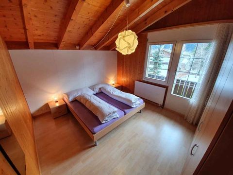 Schlafzimmer mit Doppelbett, Holzbalken und Balkontür