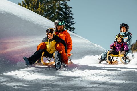 Familie beim Schlitteln im Schnee